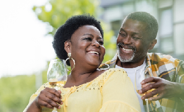 elderly man and woman smiling and wining together